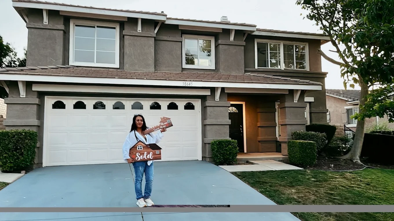 Filipino homeowner in front of her new home with sold sign